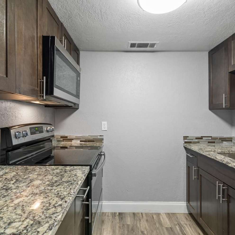 A kitchen with granite countertops and wooden cabinets.